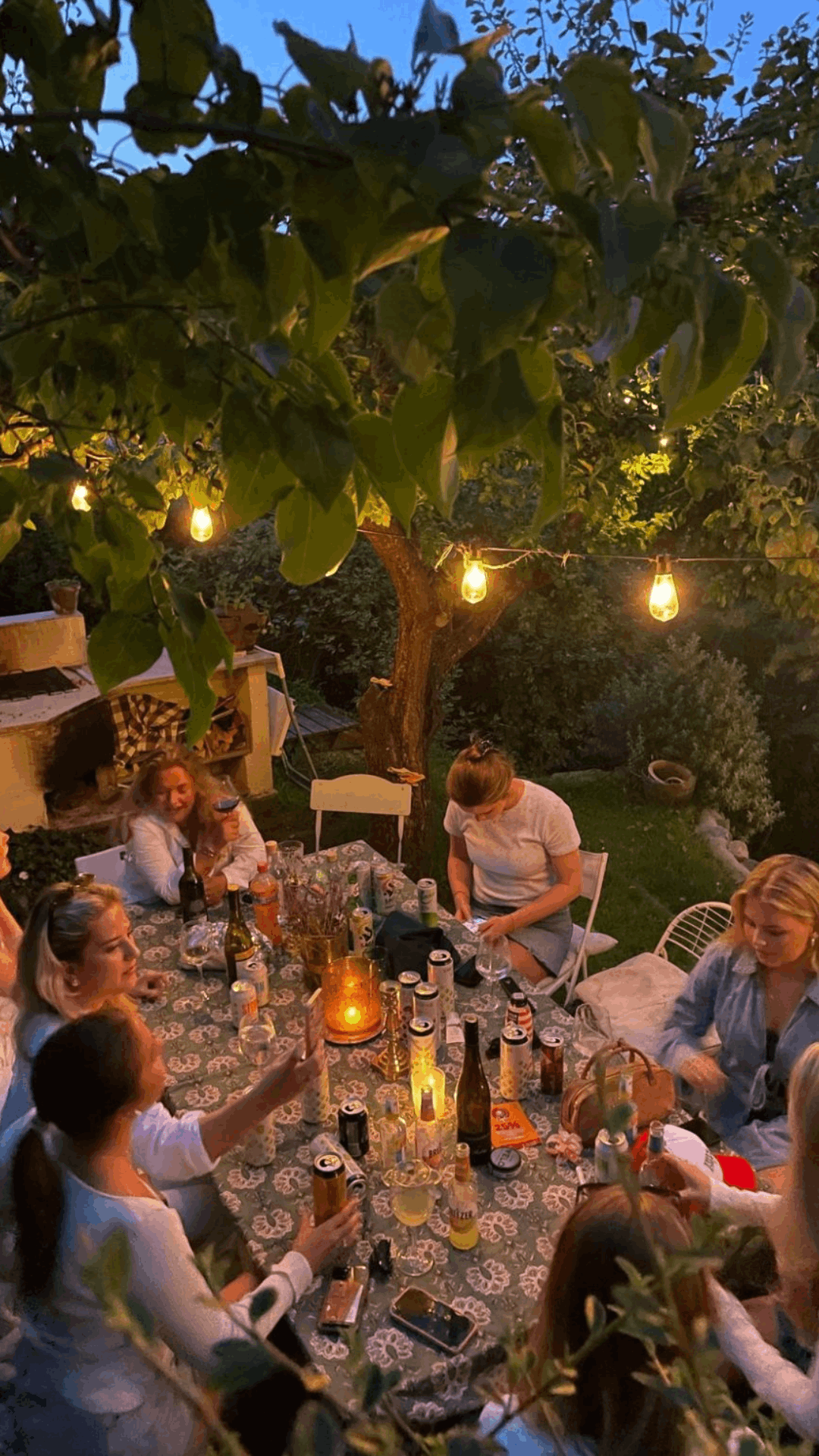 Friends sharing dinner under garden lights